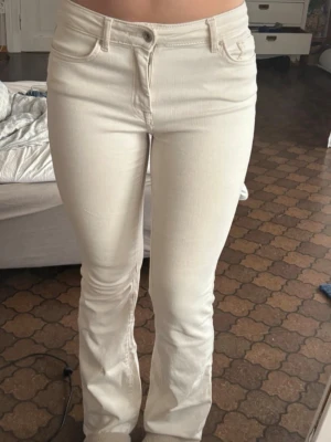 Vita bootcut jeans  - Snygga vita jeans med bootcut passform och stretchigt material. Klassisk femficksmodell med normalhög midja och knappgylf. Perfekta till en avslappnad eller trendig look.