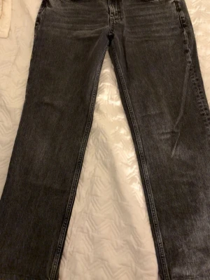 Svarta raka jeans med vintagekänsla - Säljer ett par svarta jeans med rak passform och klassisk femficksdesign. Jeansen har en snygg tvättad look som ger en vintage vibe och är tillverkade i kraftigt denimtyg. Perfekta för dig som gillar en avslappnad men stilren stil. Mina favorit byxor tyvärr blivit för små:(