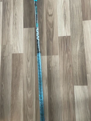 Blå FatPipe innebandyklubba med mönstrad Linda  - Säljer en innebandyklubba med blått och svart mönstrat grepp. Skaftet är mestadels svart med blå detaljer och greppet har en unik design som ger bra fäste. Perfekt för dig som vill sticka ut på planen. 94cm. Lindan behöver bytas annars nästan fel fri.