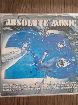 Absolute Music 23 CD-samling - Säljer en CD-samling, Absolute Music 23, med blått omslag och vattentema. Innehåller låtar från bland annat Spice Girls, Modern Talking, Eagle-Eye Cherry och Kent. Perfekt för dig som gillar pop och hits från 90-talet. Plastfodral med tryckt låtlista på baksidan.