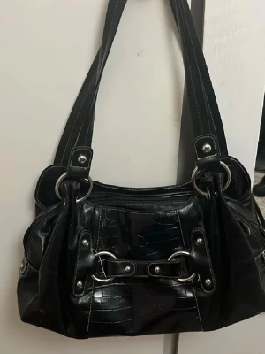 Svart handväska med crocoprägling - Väskan är jätte fin och rymlig men på små ställen har skinnet ramlat av men inget man tänker på