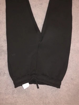 Svarta mjukisbyxor från FSBN - Svarta mjukisbyxor från FSBN med resår och dragsko i midjan samt muddar vid bensluten. Tillverkade i mjukt material som passar perfekt för chill dagar. Diskret logga på benet för en clean look. Passar s helt ny 