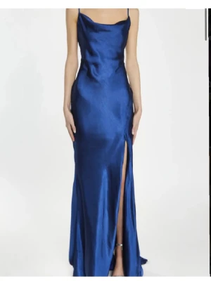 Marinblå balklänning - Marinblå klänning i satin. Klänningen är lite lång där bak då de ska vara ett sorts släp, har även ett slit vid benet. Har använts en gång! På lappen står det true decadence. De är bara o skriva om mått eller andra frågor, kan även skicka fler bilder om de önskas🩷