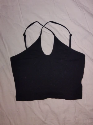 Svart croppad linnetopp - Snygg svart croppad linnetopp med tunna axelband som korsas i fram. 