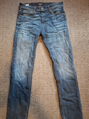 Blå jack & jones jeans - Säljer ett par blåa Jack & Jones med passform slim straight och klassisk femficksdesign, Storlek 30W 34L. Jeansen har snygga slitningar och kontrastsömmar. Perfekta för dig som gillar en tidlös och enkel stil. Skrive vid frågor.