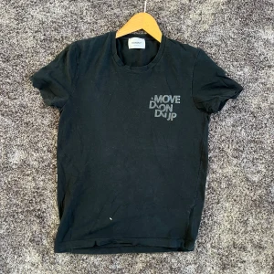 Dondup T-Shirt - Snygg svart t-shirt från Dondup med trycket 'MOVE DONDUP' på bröstet. Klassisk rund hals och korta ärmar. Tillverkad i mjuk bomull som känns skön mot huden. Perfekt till jeans eller shorts för en enkel och stilren look.