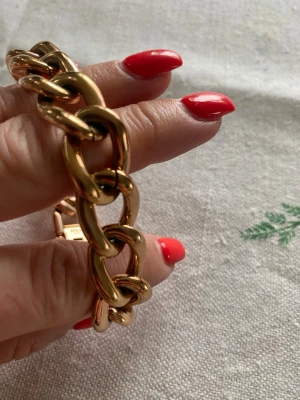 Guldfärgat kedjearmband från Edblad - Stilrent armband från Edblad i guldfärgad metall med stora, blanka länkar. Snygg chunky design som ger ett statement till din outfit. Låset är diskret och har märkets logga ingraverad. Perfekt accessoar för dig som gillar trendiga smycken.