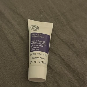 Yves Rocher anti-rynk kräm 7 ml - En liten tub med Yves Rocher Filler Végétal anti-rynk dagkräm. Tuben är vit med lila detaljer och rymmer 7 ml. Krämen är framtagen för att motverka rynkor och ge huden ett plumpande resultat. Perfekt att ha med i väskan.