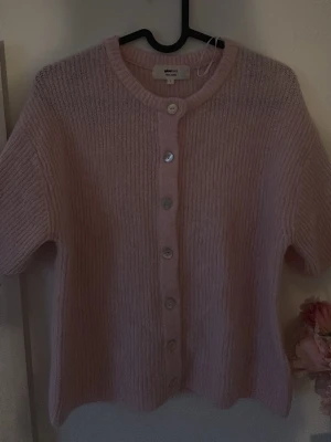 rosa kofta  - PRIS KAN DISKUTERAS! Aldrig använt Supersöt ljusrosa kofta från Gina Tricot i ullblandning. Koftan har korta ärmar, rund halsringning och knäpps med stora pärlemorknappar framtill. Perfekt att styla över ett linne eller t-shirt för en trendig lager-på-lager-look.