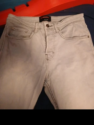 Ljusgrå raka jeans från Zara - Snygga ljusgrå jeans från Zara med klassisk femficksdesign och raka ben. Jeansen har normal midja och är tillverkade i ett mjukt denimtyg som ger en avslappnad look. Perfekta för dig som gillar stilrena och enkla jeans.