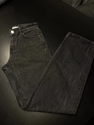 Svarta raka jeans från Pull & Bear - Säljer ett par svarta raka jeans från Pull & Bear med klassisk femficksdesign och medelhög midja. Jeansen är tillverkade i kraftigt denimtyg och har en snygg tvättad look som passar till allt. Perfekta för dig som gillar en clean och stilren vibe.