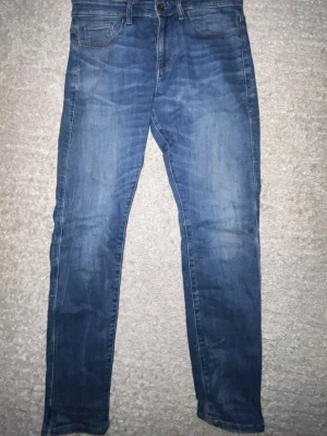 Blå slim fit jeans från G-Star RAW - Säljer ett par blå skinny fit jeans från G-Star RAW med klassisk femficksdesign och snygga slitningar. Jeansen har normal midja, dragkedjegylf och är tillverkade i mjuk denim. Perfekta för en avslappnad och trendig look.  Nypris 750kr men säljer för 350!!!!!