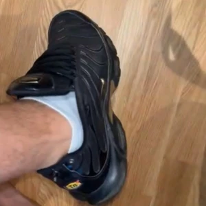 Nike Air Max plus - Köpt för 2300kr.. ÄKTAAA. Säljer ett par Nike Air Max Plus i svart med guldiga detaljer och synlig air-sula. Skorna har vågformade linjer på ovandelen, mesh och syntetmaterial samt klassisk snörning. Swoosh-logga i guld på sidan och TN-detalj vid hälen. Riktigt snygga och sportiga sneakers. Dom är inte fel fria dem har skador oså på sig