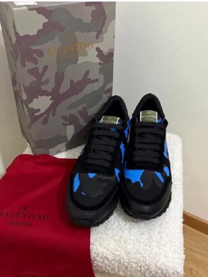 Valentino skor - Snygga sneakers från Valentino med blå och svart camo-mönster. Skorna har svarta snören, svart sula och detaljer i mocka och textil. Perfekta för dig som vill sticka ut med en unik design och exklusiv känsla.