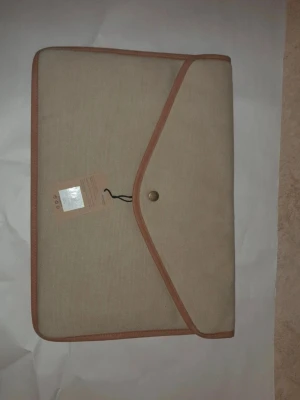 Beige datorväska från Vinga - Stilren beige datorväska från Vinga tålig med knappstängning. Perfekt för att skydda din laptop och hålla stilen på språng. Slimmad design som passar enkelt i ryggsäcken eller under armen.