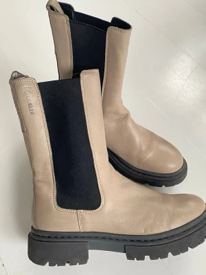 Beige Chelsea boots från W.Cobler - Snygga beige Chelsea boots från K.Cobler Scorett med chunky svart sula och bred resår i sidan. Modellen heter Maldon boots.  Tillverkade i slätt läder med klassisk rund tå och högt skaft. Storlek 39 som passar mig 39.5 perfekta. Fint skick.