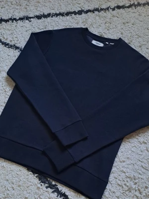 Svart sweatshirt från Filippa K - En stilren mörkblå sweatshirt med rund halsringning och ribbade muddar vid ärmslut och nederkant. Perfekt basplagg i mjukt material som passar till allt. Enkel och clean design utan tryck eller mönster.