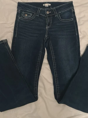Mörkblå jeans från Gina med vita sömmar - Snygga mörkblå bootcut jeans med vita sömmar, säljer eftersom att dom är för små för mig som är 164 cm lång och har normalt storlek 170 i jeans. Jeansen är använda några gånger och dom är i väldigt bra skick för att vara 2 år gamla. Vet inte om modellen säljs längre. 