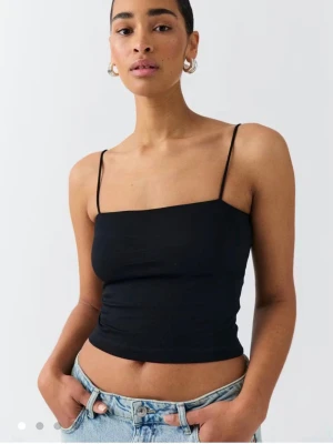 Svart croppad linnetopp - Snygg svart croppad linnetopp med tunna axelband. Perfekt till jeans eller kjol för en trendig look. Enkel och stilren topp som passar till många outfits. 