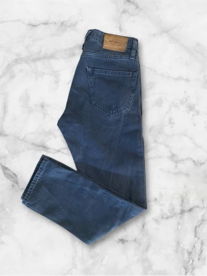 Blå raka jeans från Jack & Jones - Säljer ett par blå jeans från Jack & Jones med klassisk femficksdesign och raka ben. Jeansen har en snygg tvättad look och är tillverkade i mjuk bomullsdenim. Perfekta för en avslappnad stil och passar till det mesta.