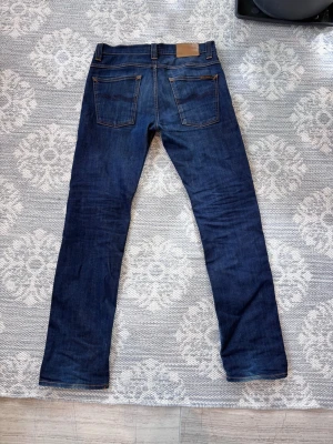 Nudie jeans average joe dry - Storlek 31/32 mycket fint skick, hlr av er vid frågor.    Snygga mörkblå jeans med raka ben och klassisk femficksdesign. Jeansen har kontrastsömmar och en läderpatch bak i midjan. Perfekta för en stilren och avslappnad look.
