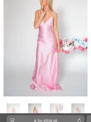 Lång rosa satinklänning med smala axelband - Elegant långklänning i ljusrosa satin från By Stina. Klänningen har smala axelband och v-ringad front, vilket ger en stilren och feminin look. Perfekt för speciella tillfällen och högtider. Jag har haft den på mig bara en gång på min bal. 