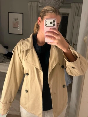 Beige trenchcoat med dubbelknäppning - Snygg beige trenchcoat som är i bra skick, säljer då den inte kommer till användning💕Perfekt nu till våren men också hösten och vintern💕