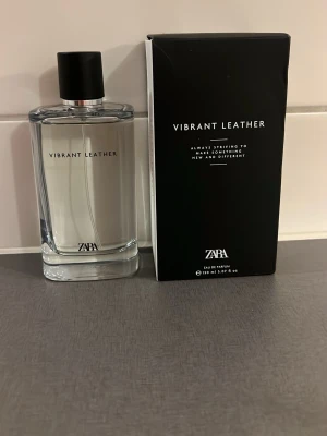 Zara Vibrant Leather parfym 100 ml - Zara Vibrant Leather är en stilren parfym i en genomskinlig glasflaska med svart lock. Doften kommer i en svart kartong med minimalistisk design. Perfekt för dig som gillar eleganta och moderna dofter.