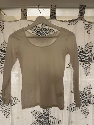 Vit långärmad topp med rund hals - En enkel och stilren vit långärmad topp med rundad halsringning. Toppen har en tight passform och är tillverkad i ett mjukt bomullsmaterial som känns skönt mot huden. Perfekt att matcha med jeans eller kjol för en clean look.