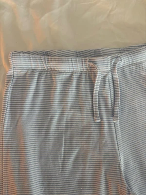 Ljusblå randiga mjukisbyxor - Mysiga ljusblå mjukisbyxor med tunna vita ränder. supermjuka och sköna! precis blivit för korta för mig som är ca 164 passar definitivt nån som är under 160! 