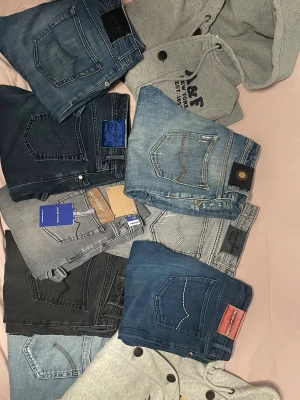 Mix av jeans i olika tvättar - Säljer ett gäng snygga jeans i olika blå och grå tvättar, både ljusa och mörka. Flera olika märken och modeller, vissa med detaljer som kontrastsömmar och patchar. Perfekta för dig som vill ha variation i garderoben!