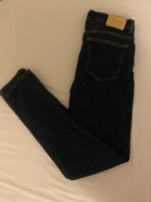 Mörkblå jeans från GANT - Snygga mörkblå jeans från GANT med klassisk femficksdesign och kontrastsömmar. Jeansen har en stilren look och är perfekta för dig som gillar en tidlös stil. Materialet är jeans och de har en normal passform. Priset diskuterbart