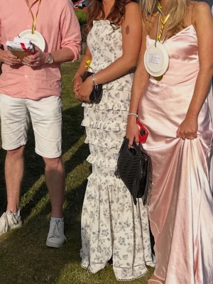 Vit blommig långklänning med volanger - Vit lång blommig sommarklänning som passar perfekt till bal och andra festligheter. Klänningen är armlös och sitter figurnära. Storlek M, men jag har sytt om den så den passar perfekt för mig som normalt har S. Skriv för fler bilder eller funderingar🤍🌸