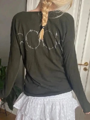 Mörkgrön tröja med broderi Zadig & Voltaire  - Mysig mörkgrön långärmad tröja med v-ringning och broderad text på ryggen. Tröjan har en avslappnad passform och är tillverkad i ett mjukt material som passar perfekt till vardagslooken. Zadig