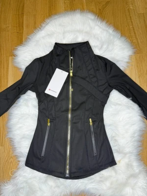 Svart Nulu define jacket Lululemon i Stl.2 - Den lite mindre och smalare versionen av lululemons define jacket i Stl. 2 som motsvarar runt XS eller en riktigt tight S. Jag hade rekommenderat XS för bäst passform. Den är helt oanvänd och ren! 💞💞