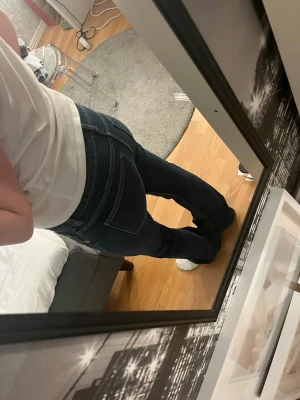 Mörkblå bootcut jeans - Säljer ett par mörkblå bootcut jeans med klassisk femficksdesign och normalhög midja. Jeansen har utsvängda ben och är tillverkade i denim med lätt stretch för skön passform. Perfekta för dig som gillar en tidlös och avslappnad stil.