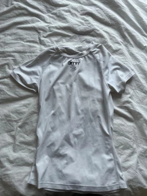 Vit sporttröja från Aimn - Säljer en vit, kortärmad sporttröja från Aimn med rund hals och figurnära passform. Tillverkad i ett stretchigt funktionsmaterial som passar perfekt till träning och aktivitet. Diskret logga framtill vid halsen.