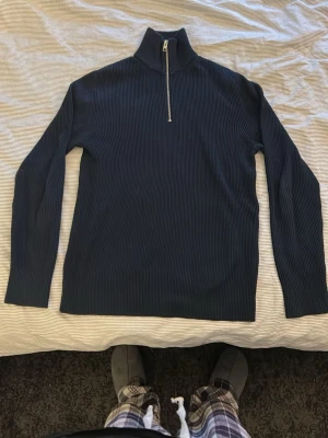 Mörkblå ribbstickad tröja med halvzip - Säljer en mörkblå ribbstickad tröja från Morris med hög krage och halv dragkedja framtill. Tröjan har långa ärmar och är tillverkad i ett mjukt, stretchigt material som ger en clean och stilren look.