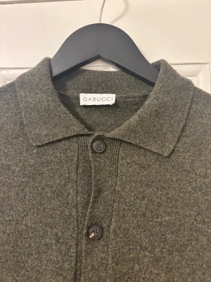 Mörkgrön kofta från Gabucci - Stilren mörkgrön kofta från Gabucci med klassisk krage och knäppning framtill. Koftan har långa ärmar och ribbade muddar vid ärmslut och nederkant. Använt ett fåtal gånger och i toppen skick utan nopprar eller slitningar. Super snygg tröja för killar som passar alla i en storlek S/50.