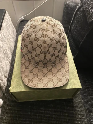 Beige GG Supreme keps från Gucci - Säljer en beige keps från Gucci med det klassiska GG Supreme-mönstret över hela kepsen.