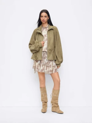 Grön mockajacka med snörning - Trendig oliv grön mockajacka med ballongärmar och snörning i midjan. Jackan har hög krage och dragkedja framtill, vilket ger en cool och avslappnad look. Perfekt för dig som vill sticka ut med en unik siluett.