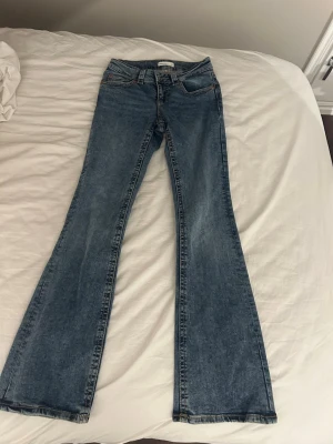 Blå bootcut jeans med utsvängda ben - Säljer ett par klassiska blå bootcut jeans med utsvängda ben och femficksmodell. Jeansen har låg midja. Aldrig använda 