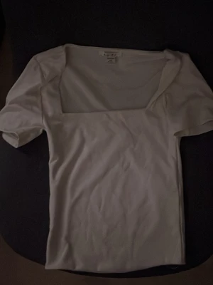 Vit topp med fyrkantig urringning - Trendig vit topp från new yorker med korta ärmar och snygg fyrkantig urringning. Tillverkad i ett mjukt och stretchigt material som sitter skönt på kroppen. 