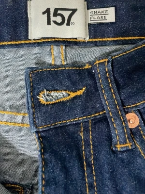 Mörkblå snake flare jeans 157 - Snygga mörkblå flare jeans från 157 med klassiska kontrastsömmar och utsvängda ben. Modellen heter Snake Flare och har en retroinspirerad passform som ger en cool siluett. Perfekta för dig som gillar vintagevibbar och statement-jeans.