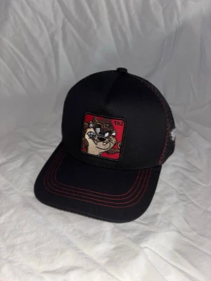 Svart/röd Taz keps - ✦ Helt ny 🆕 ✦ Justerbar ✅ ✦ One size 👤 ✦ Snabb frakt 🚚 ✦ Frågor eller fler bilder? Skriv 📩