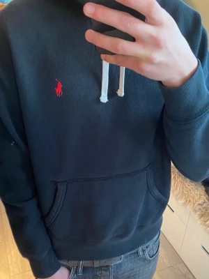 Ralph Lauren hoodie - |Tja! En otroligt snygg och eftertraktad Polo Ralph Lauren hoodie i en skön färg ❗️| Skick 8/10 bra skick, ett pyttelitet hål som lagats vid höger axel☑️| Storlek: M , sitter som S, sitter lite litet på mig - 189cm 75kg📏| Nypris: ca 2000kr💵| Färg: svart, som på bilden🖤| Fraktar spårbart via postnord eller instabox📦| Hör av er för mer information!|