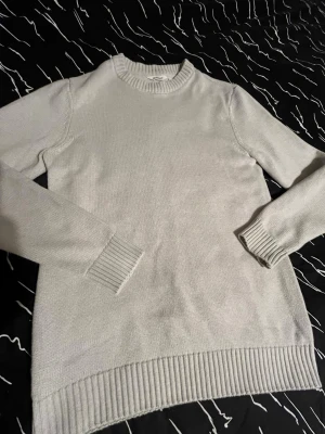 Ljusbeige stickad tröja från dobber - En enkel och stilren ljusbeige stickad tröja med rund halsringning och ribbade muddar vid ärmslut och nederkant. Tröjan har lång ärm och är perfekt för lager på lager. Materialet känns mjukt och bekvämt. Bra skick med inga synliga täcken på användning, inga hål eller defekter. Storlek S