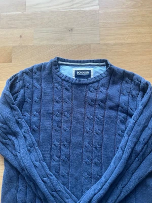 Marinblå kabelstickad tröja Bondelid - Snygg marinblå kabelstickad tröja från Bondelid. Tröjan har rund halsringning och ett klassiskt flätmönster över hela plagget. Perfekt för dig som gillar en stilren och tidlös look. Tillverkad i mjukt stickat material.