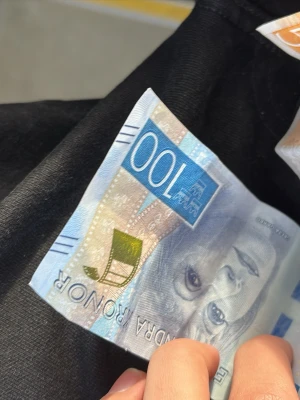 Svensk 100-kronorssedel - Säljer en svensk 100-kronorssedel med blå och gröna detaljer samt porträtt av Greta Garbo. Sedeln har moderna säkerhetsdetaljer och är tillverkad i papper med inslag av plast.