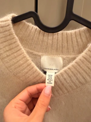 Beige croppad stickad tröja H&M - Supermjuk och fluffig beige stickad tröja från H&M i mohair- och ullblandning. Tröjan har croppad passform, v-ringning och långa ärmar med ribbade muddar. Perfekt för lager-på-lager och en chill look.